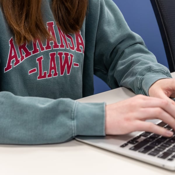 Student in Arkansas Law sweatshirt takes notes on a laptop in class