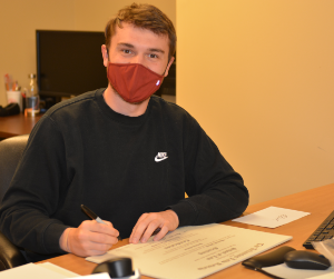 photo of Nick Bell signing certificates at a desk